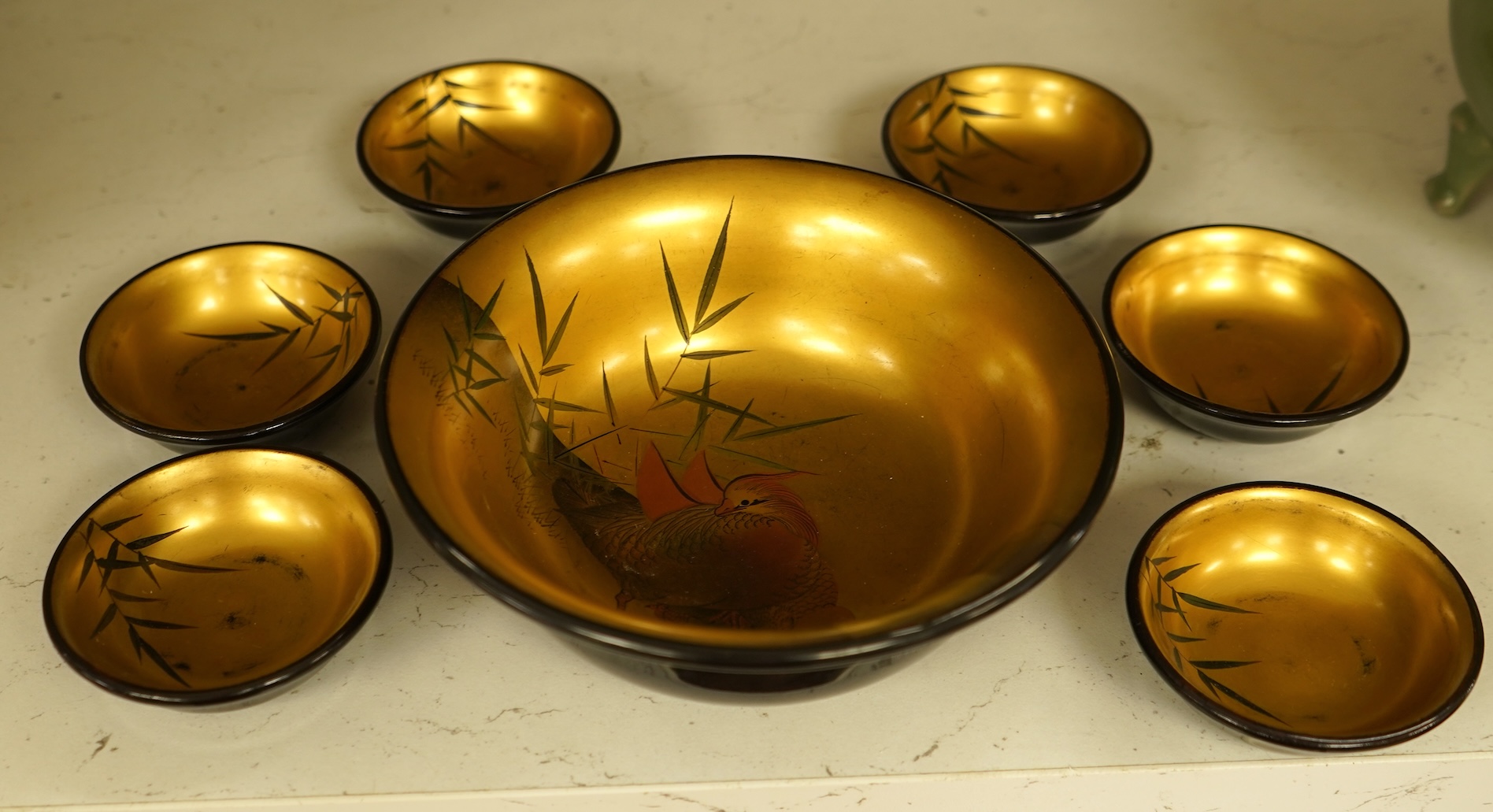 A Japanese lacquer bowl with gilt interior decorated with birds and six small dishes, largest 15cm in diameter